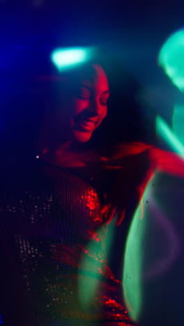 Vertical-Video-Of-Young-Woman-In-Nightclub-Bar-Or-Disco-Dancing-With-Sparkling-Lights-In-Background
